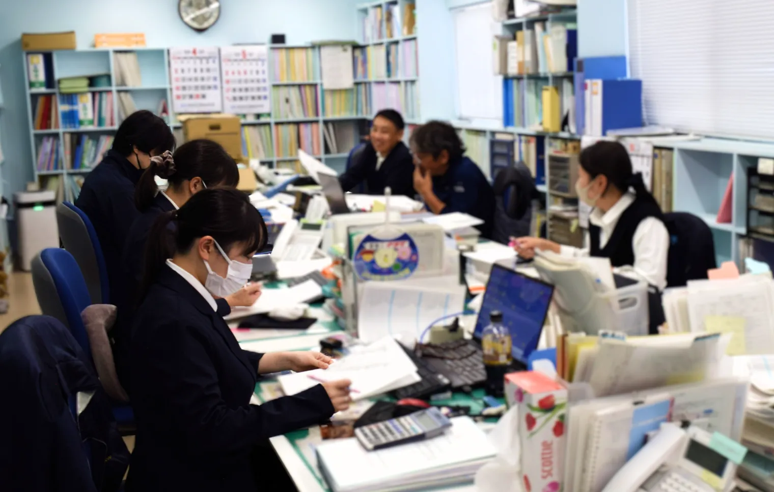 折本設備の事務所で書類業務を分担して進めるスタッフたち